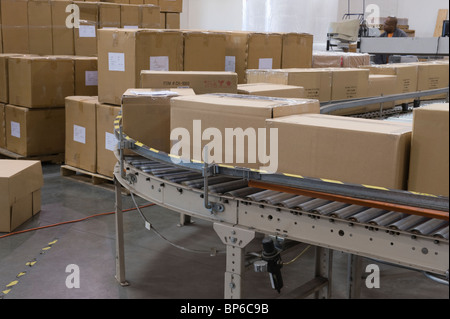 Cardboard boxes on conveyor belt in distribution warehouse Stock Photo