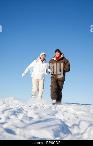 Young couple holding hands, running in snow Stock Photo