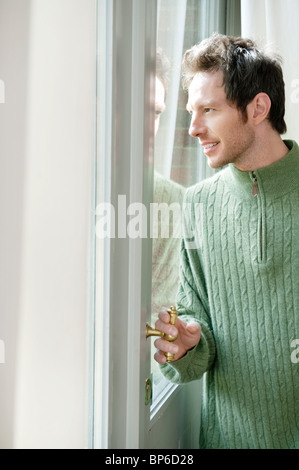 Man looking out through a door glass Stock Photo