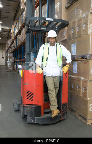 Man standing with fork lift truck in distribution warehouse Stock Photo