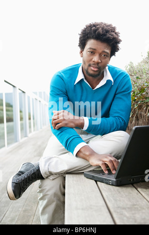 Man using a laptop on a boardwalk Stock Photo