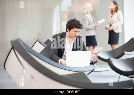 Businessman sitting in a waiting room and using a laptop Stock Photo