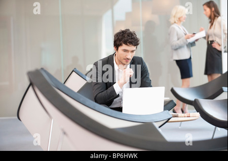 Businessman sitting in a waiting room and using a laptop Stock Photo