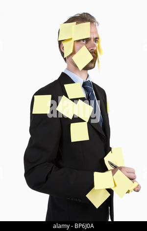 A man covered in blank adhesive notes and holding a pen Stock Photo