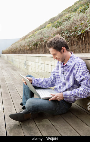 Man using a laptop and listening to music Stock Photo