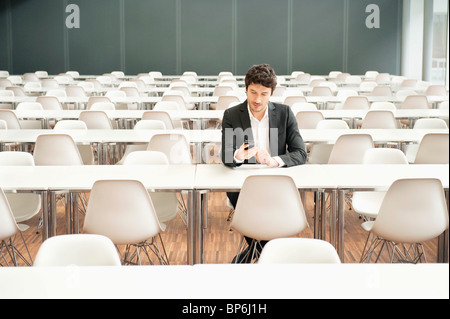 Businessman sitting at a cafeteria and using a mobile phone Stock Photo