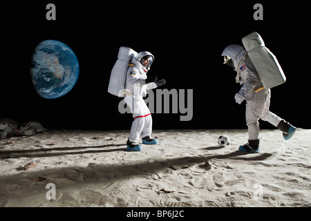 Two astronauts playing soccer on the moon Stock Photo