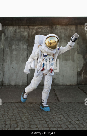 An astronaut on a city sidewalk pretending to take off in flight Stock Photo