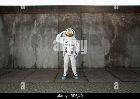 A saluting astronaut standing on a sidewalk in a city Stock Photo