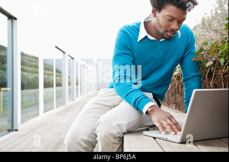 Man using a laptop on a boardwalk Stock Photo