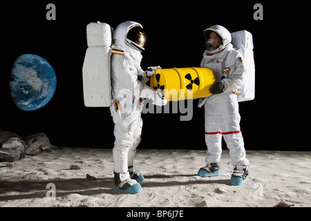 Two astronauts on the moon surface carrying a drum of toxic material Stock Photo