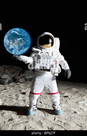 An astronaut on the moon's surface pretending to hold the earth Stock Photo