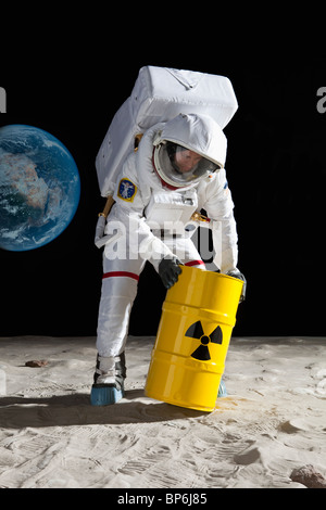 An astronaut rolling a drum of toxic material on the moon surface Stock Photo