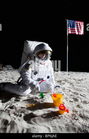 An astronaut playing with a sand pail and shovel on the moon Stock Photo