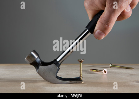 A man using a claw hammer to pull out a nail, detail of hand Stock Photo