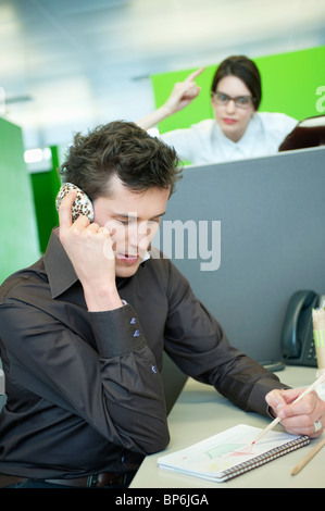 Businessmen talking on a mobile phone while his colleague looking angry Stock Photo