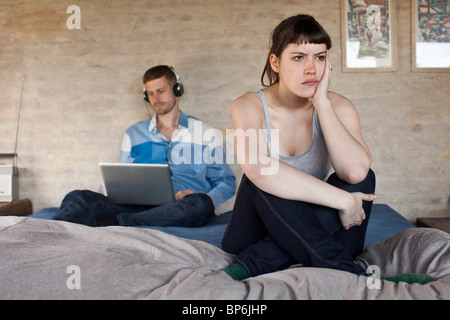 A man using a laptop and ignoring his frustrated girlfriend Stock Photo