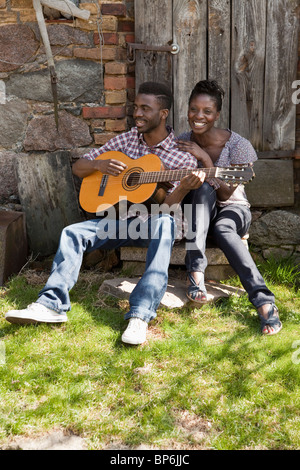 A man playing an acoustic guitar with his girlfriend Stock Photo