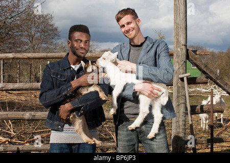 Two male friends holding kid goats Stock Photo