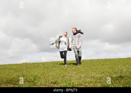 A couple running down a hill while holding hands Stock Photo