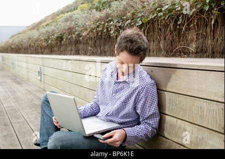 Man using a laptop on a boardwalk Stock Photo