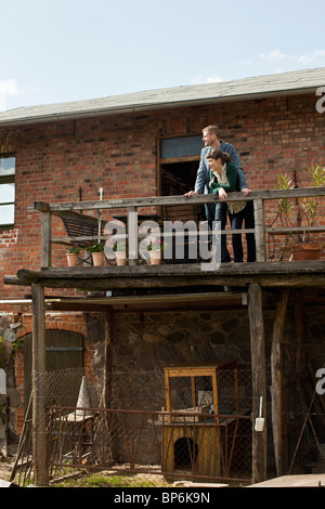 A couple standing on a balcony looking into the distance Stock Photo