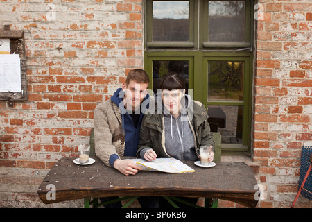 A couple with a map having lattes at an outdoor cafe Stock Photo