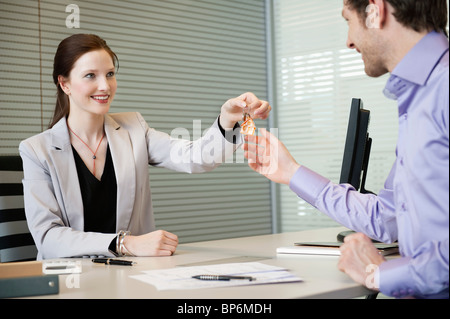 Female real estate agent giving house keys to a man Stock Photo