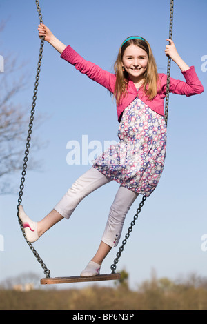 A girl standing on a swing Stock Photo