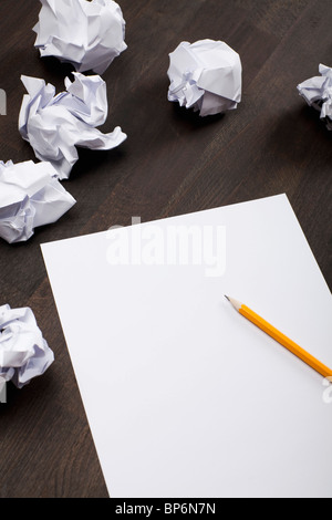 Crumpled paper balls and a blank piece of paper with a pencil Stock Photo