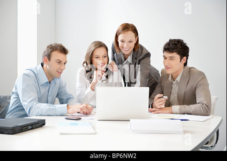 Business executives looking at a laptop in a board room Stock Photo