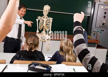 A teacher points while his students raise their hands in a biology class Stock Photo