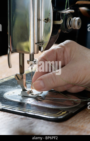 A woman threading a needle on a sewing machine, detail of hand Stock Photo