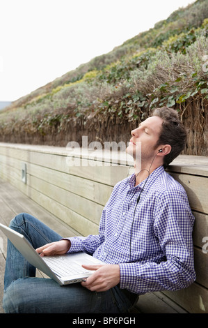 Man using a laptop and listening to music Stock Photo