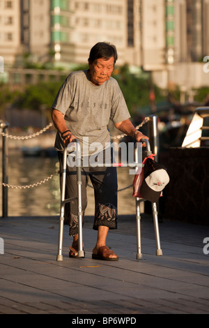 An aged person taking an early morning walk with a walking support device in the Sai Wan Ho district, Hong Kong. Stock Photo
