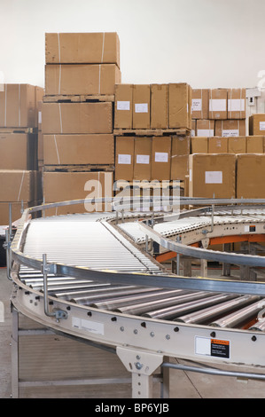 Cardboard boxes and conveyor belt in distribution warehouse Stock Photo