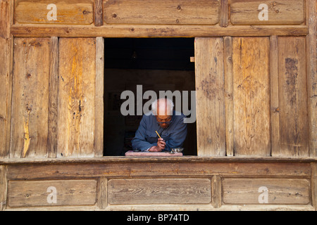 Old man writing in Shaxi Village, Yunnan Province, China Stock Photo