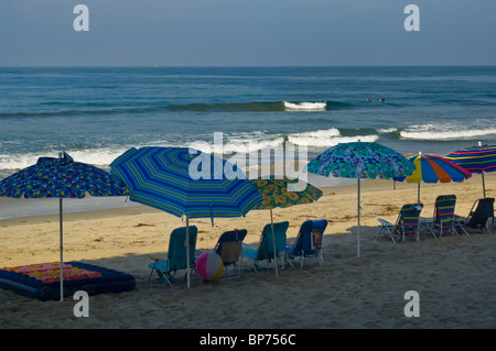 Empty chairs and shade umbrellas lined up in a row in early morning on Carlsbad State Beach, Carlsbad, San Diego, California Stock Photo