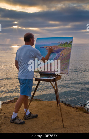 Artist Bill Jewell plein aire painting on coastal bluff overlooking the ocean at Sunset Cliffs, San Diego, California  Stock Photo