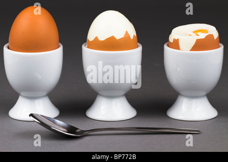 three egss on grey background with spoon in front Stock Photo
