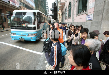 People waiting for a green light at a pedestrian crossing, Macao, China Stock Photo