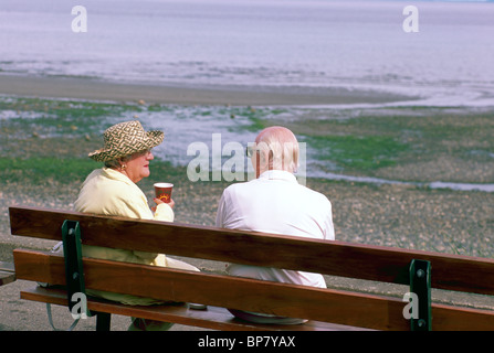 Elderly Couple, Senior Man and Woman sitting Outdoors on a Seaside Park Bench, Qualicum Beach, BC, British Columbia, Canada Stock Photo