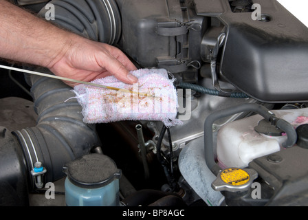 A mechanic inspects the level of oil on a car engine dipstick. Stock Photo