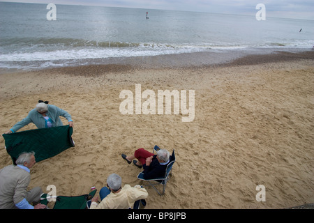 southwold, suffolk, pensioners elderly people on Southwold beach putting blanket on beach for picnic Stock Photo