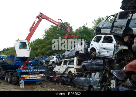 Man working on a crane at a recycling cars scrapyard UK Stock Photo