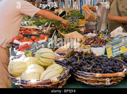 melons and grapes in a basket on a market stall in France, price in Euros, people trading Stock Photo