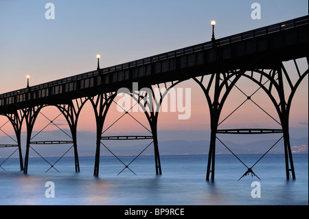 An abstract of the walkway of Clevedon Pier, North Somerset, silhouetted against a pastel sky after sunset. Stock Photo