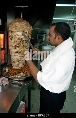 An Egypt born cook cuts Shawarma meat in a working class down town restaurant in Aqaba, Jordan Stock Photo