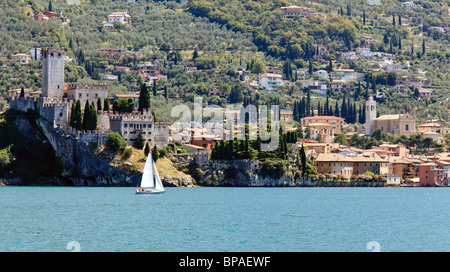 Sailing boat off the coast of Malcesine on Lake Garda , Italy with the castle framing the town Stock Photo