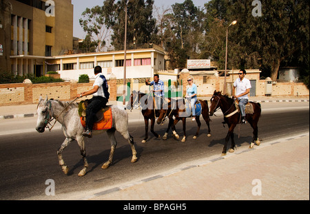 Guide on horseback leading tourists toward the Great Pyramid of Gizah in Egypt in the early morning Stock Photo